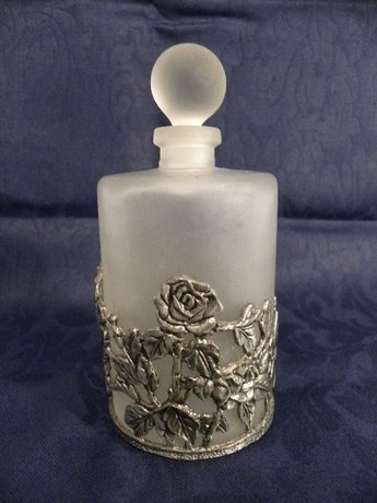 A glass scent bottle with removable white metal sleeve